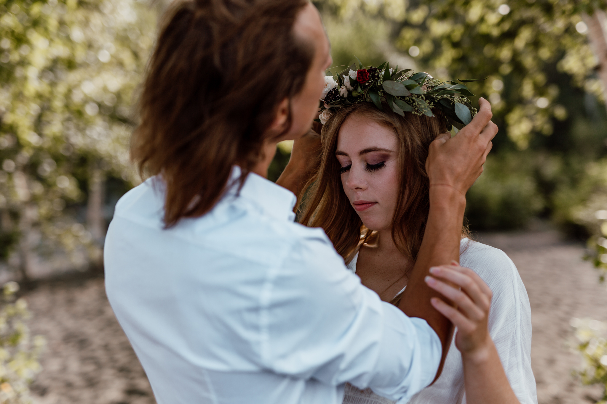 groom gently placing flower crown on bride 
