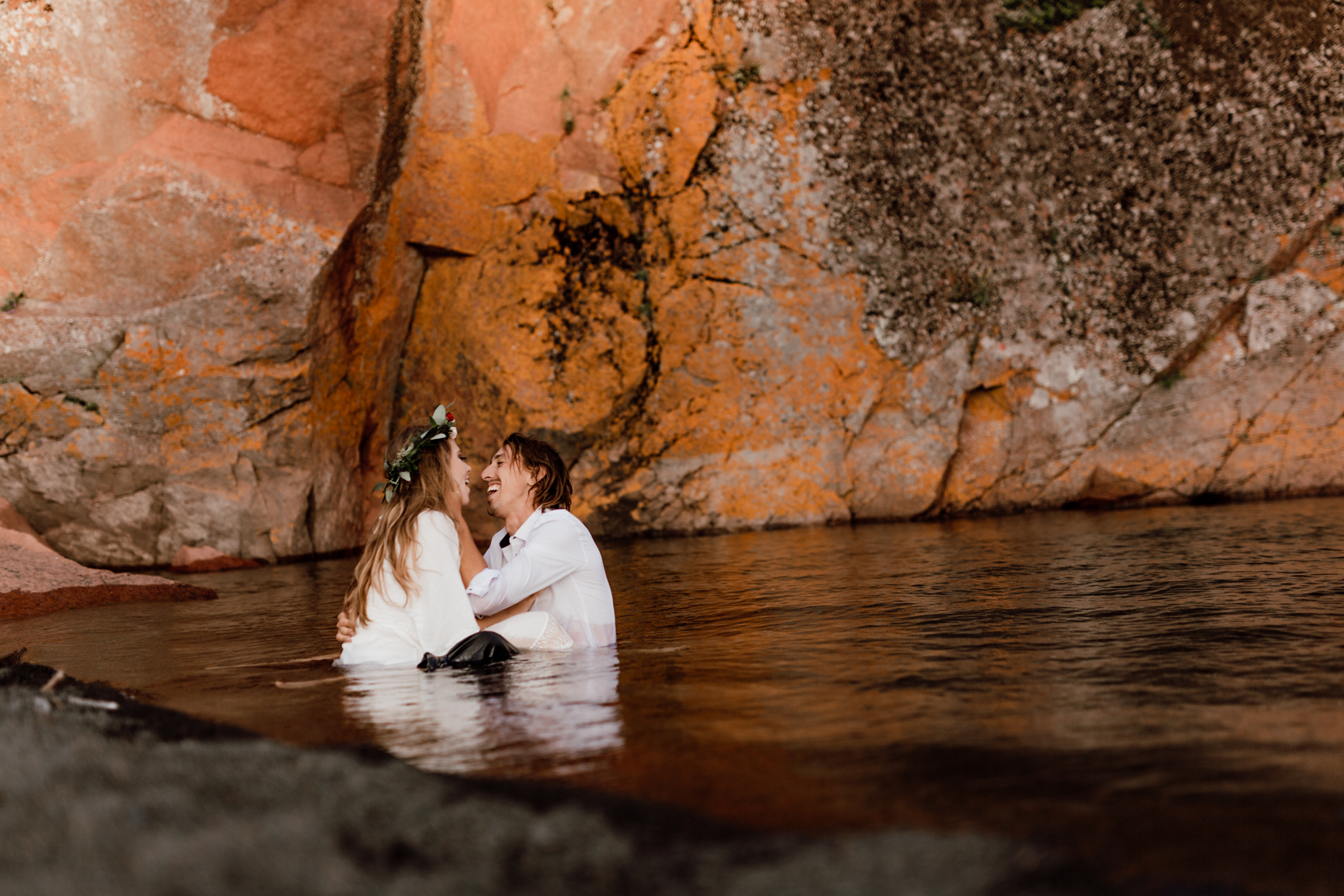 elopement portrait with couple sitting in the lake facing each other 