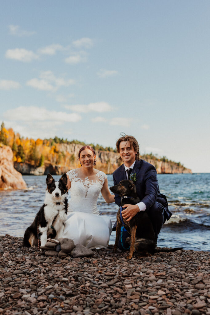 married couple portrait with their dogs on the beach with lake surperior in the background 
