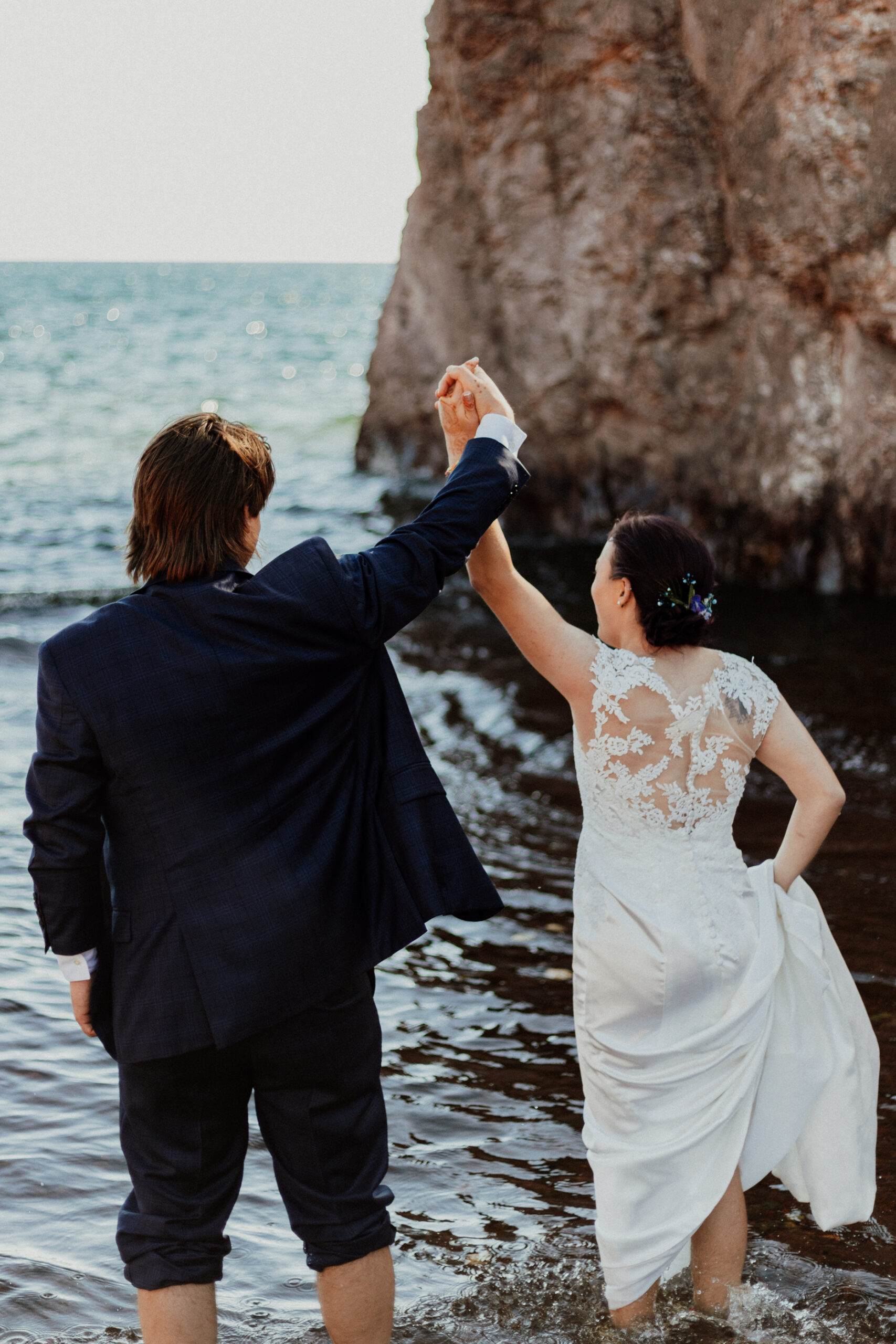 bride and groom in the waters holding hands and cheering 
