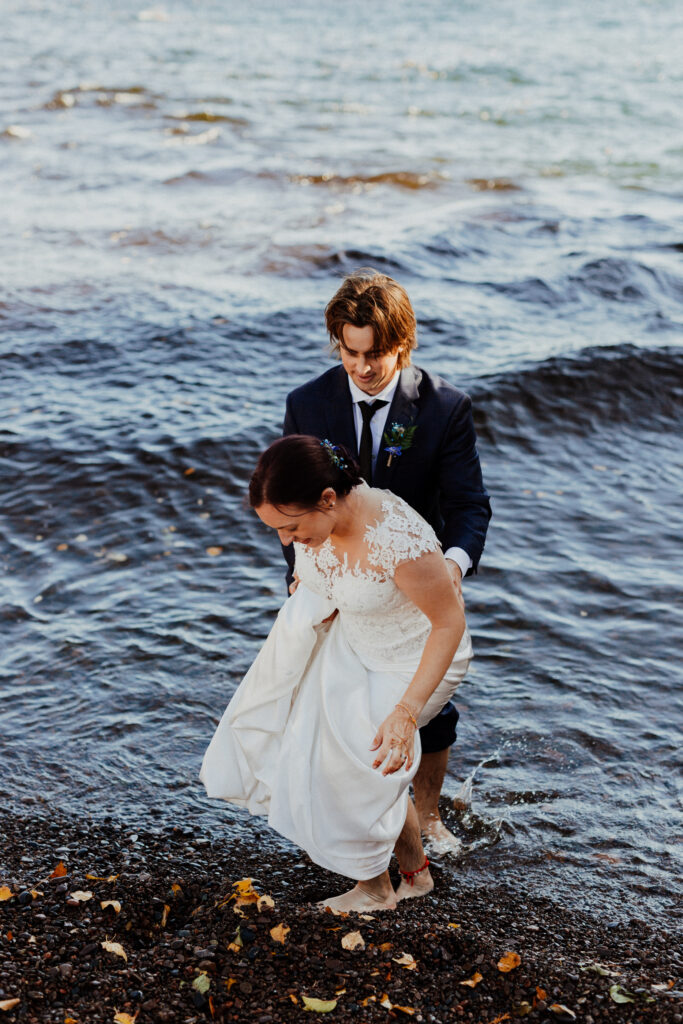 bride and groom take a step in Lake Superior's waters right after their ceremony