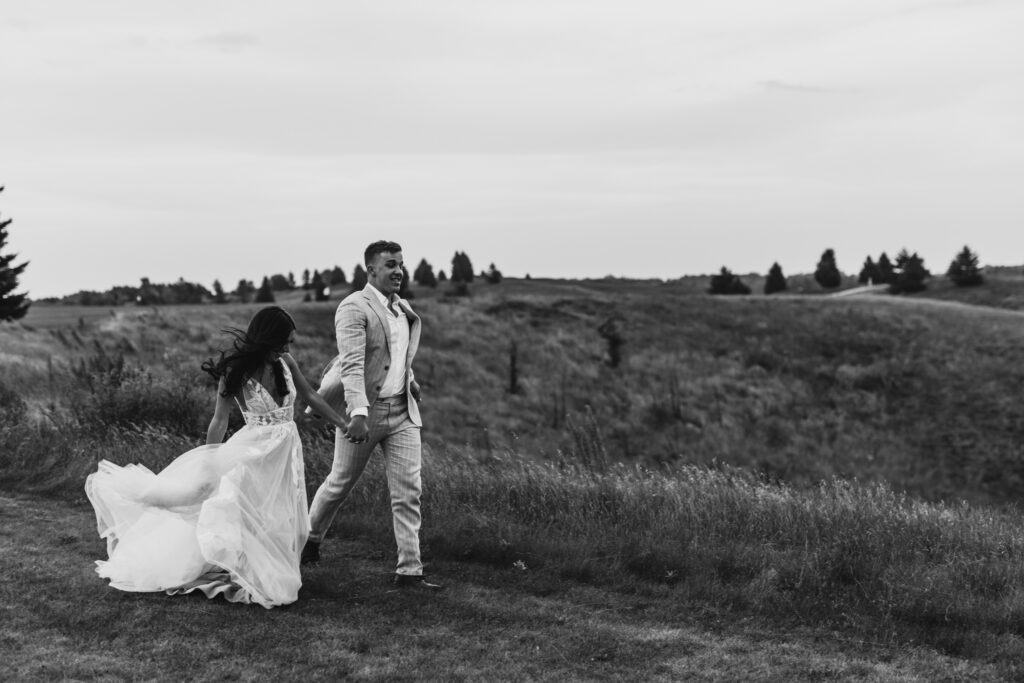 black and white action shot of couple running in a field 