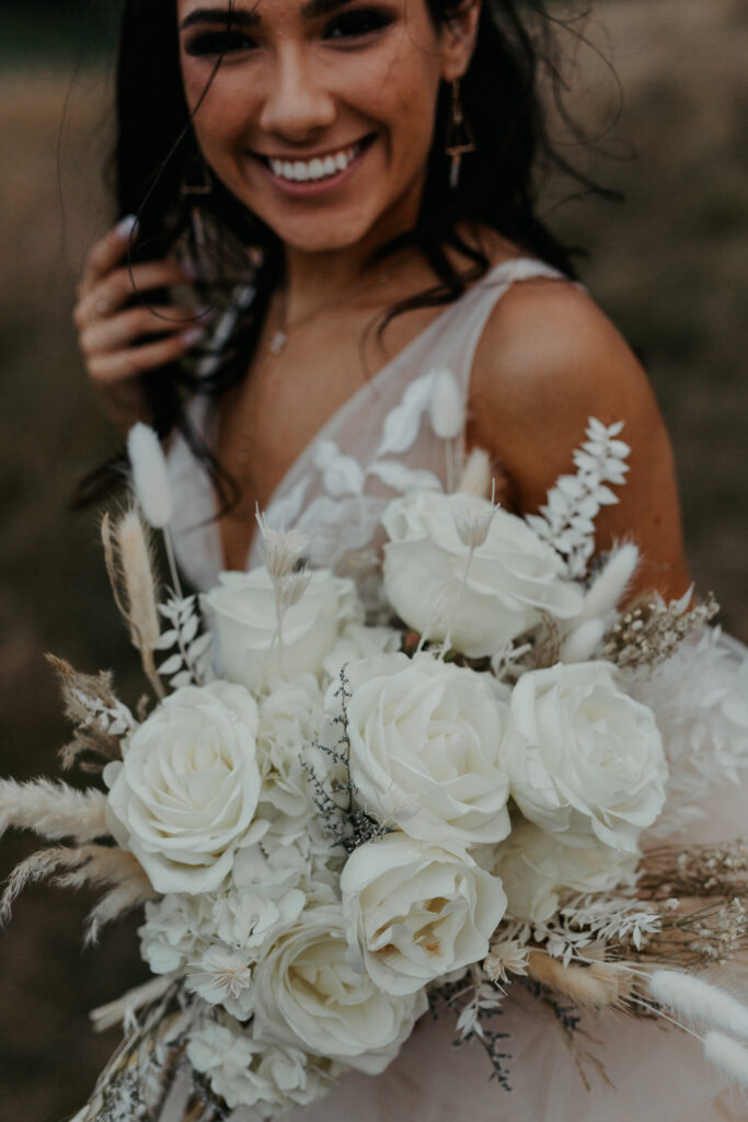 bride smiling showing off her flower bouquet 