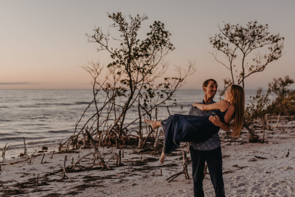engagement photo taken at blue hour along a Florida beach where Tyler picked up Brooke and carried her