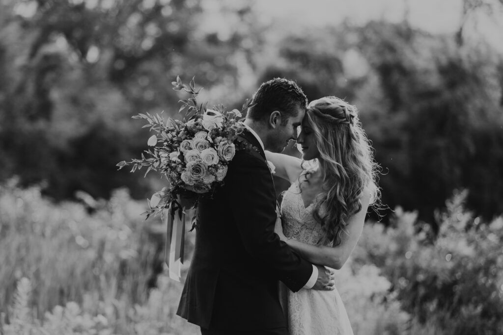 black and white image of bride and groom holding each other and closing their eyes to take in the moment 