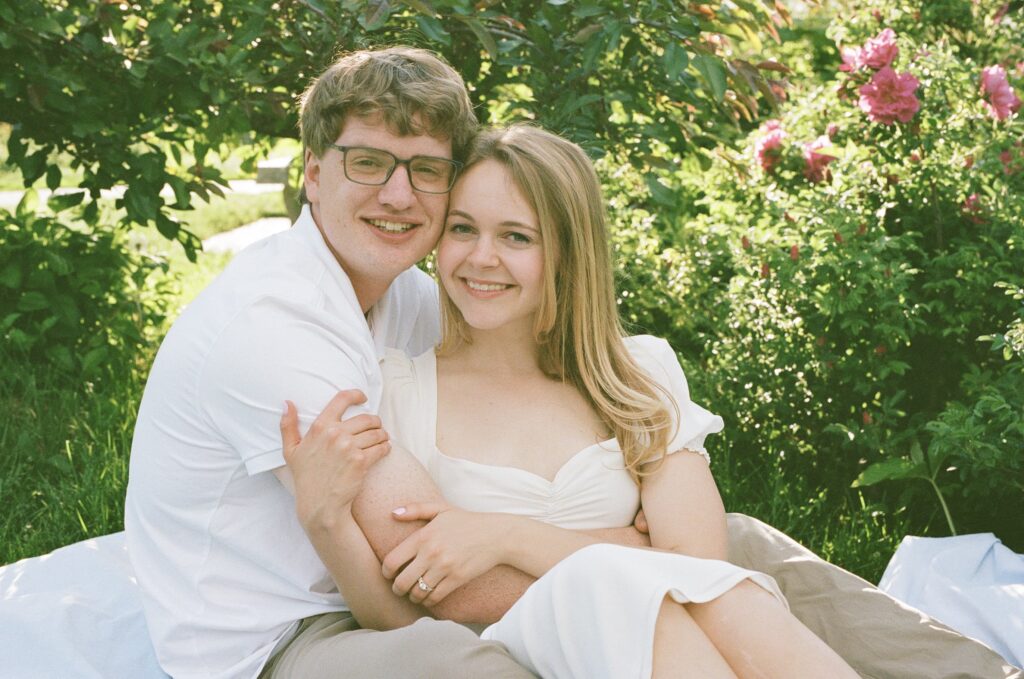 film photograph of couple snuggled together on a picnic blanket at a park engagement photography