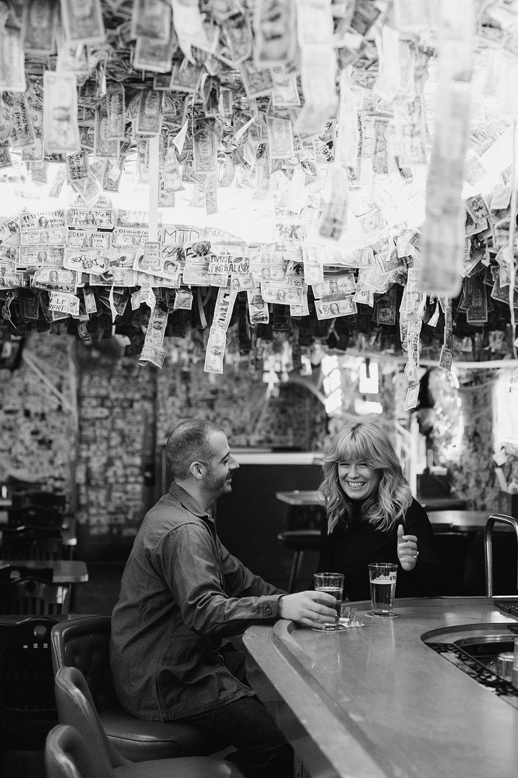 Couple cheering their drinks in a dive bar at their engagement session