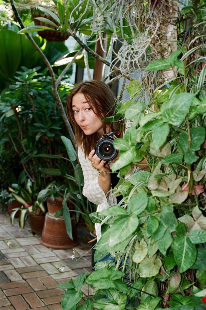 photographer with camera in hand peeking around the corner