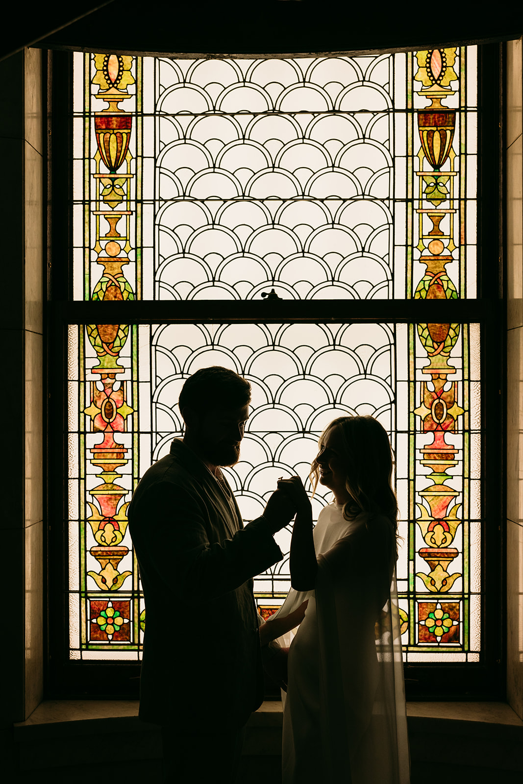 backlit couple holding hands showing off the stained glass